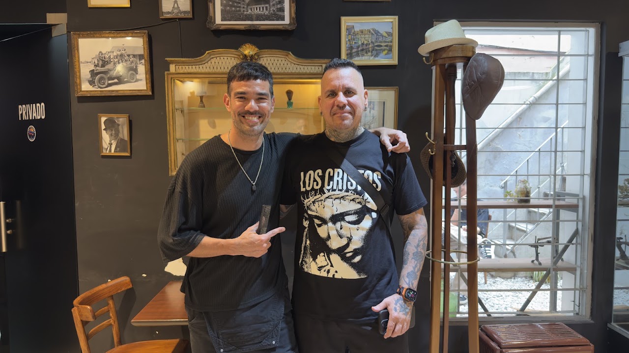 Barbero profesional aplicando vaporizador sobre el rostro del cliente para preparar la piel en ambiente sofisticado